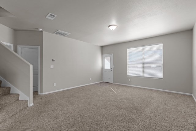 spare room featuring stairway, baseboards, carpet, and visible vents