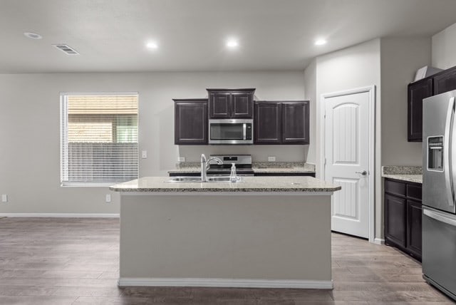 kitchen with light stone counters, visible vents, stainless steel appliances, and a sink