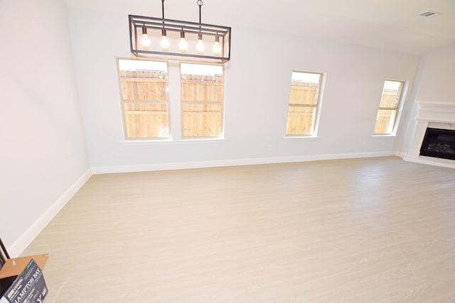 unfurnished living room featuring a premium fireplace and light hardwood / wood-style flooring