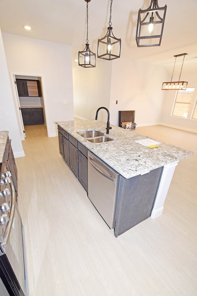 kitchen with pendant lighting, sink, a kitchen island with sink, light stone counters, and stainless steel dishwasher