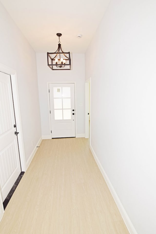 doorway with a notable chandelier and light wood-type flooring