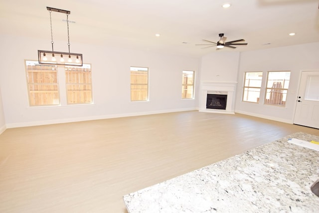 unfurnished living room featuring ceiling fan, light wood-type flooring, and a fireplace