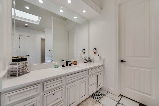 bathroom featuring tile patterned flooring, vanity, a skylight, and ornamental molding