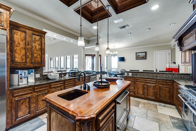 kitchen with appliances with stainless steel finishes, a kitchen island with sink, crown molding, and sink