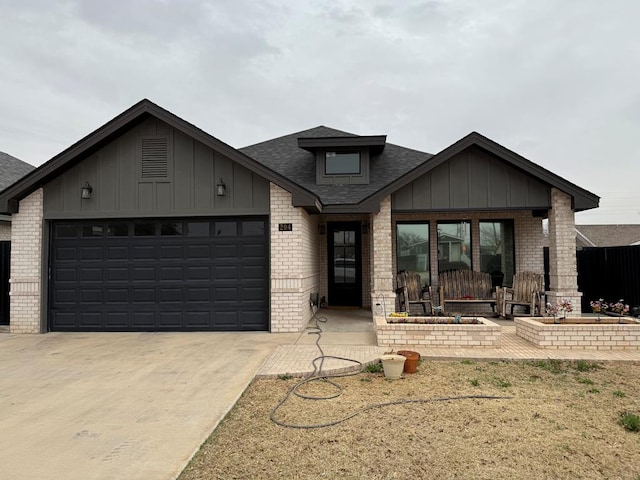 view of front facade with driveway, a garage, a shingled roof, board and batten siding, and brick siding