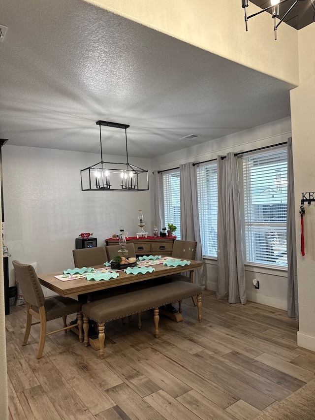 dining area featuring light wood-style floors, plenty of natural light, and a textured ceiling