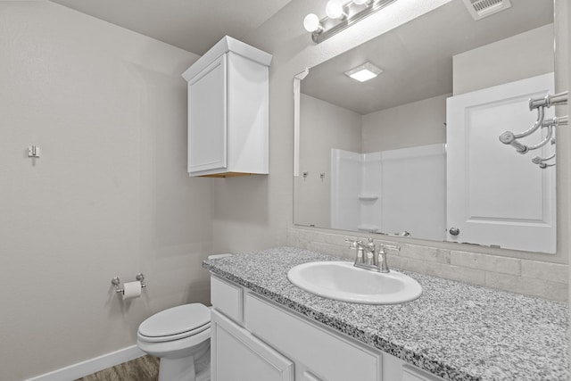 bathroom with hardwood / wood-style floors, vanity, decorative backsplash, toilet, and walk in shower