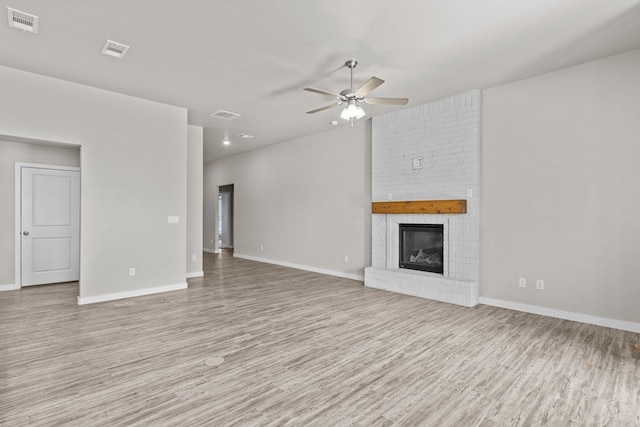 unfurnished living room with ceiling fan, a fireplace, and light hardwood / wood-style flooring