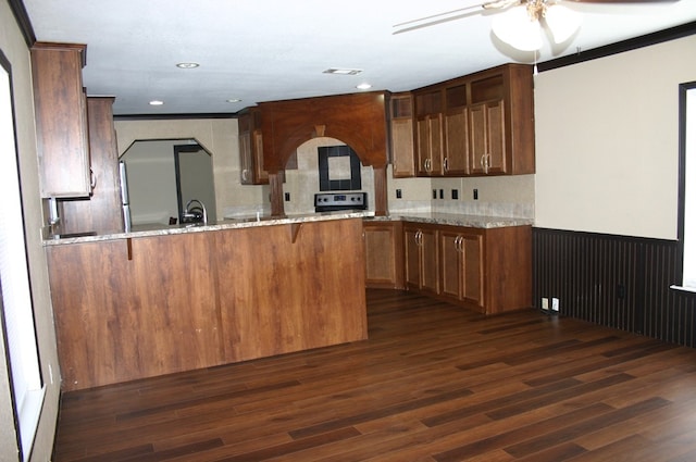 kitchen with kitchen peninsula, light stone countertops, dark hardwood / wood-style flooring, and range