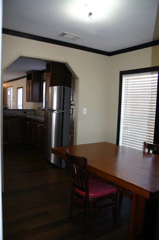 dining area featuring a textured ceiling, dark hardwood / wood-style flooring, and ornamental molding