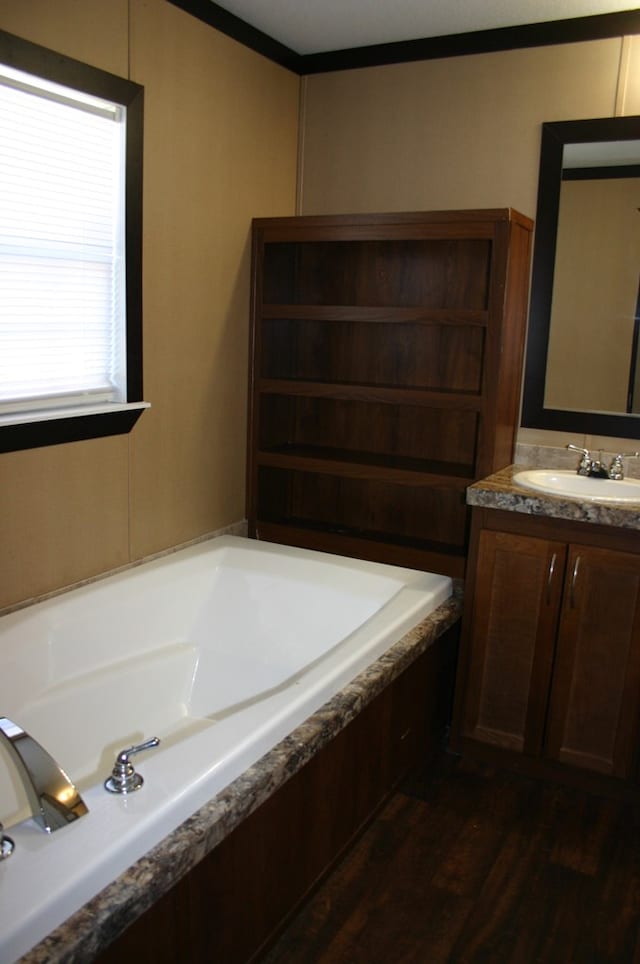 bathroom featuring a washtub, wood-type flooring, crown molding, and vanity