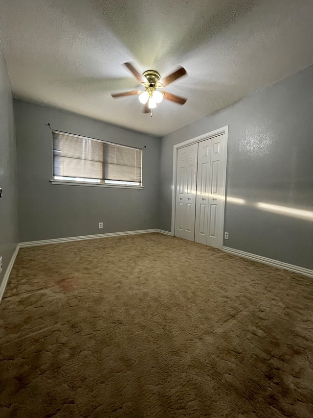 unfurnished bedroom featuring carpet, a closet, a textured ceiling, and baseboards