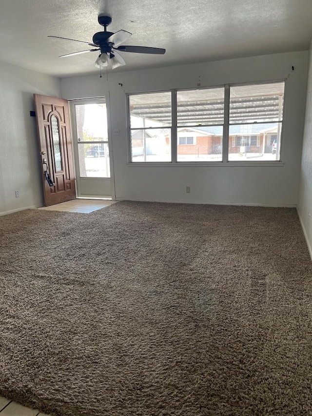 carpeted spare room featuring ceiling fan and a textured ceiling