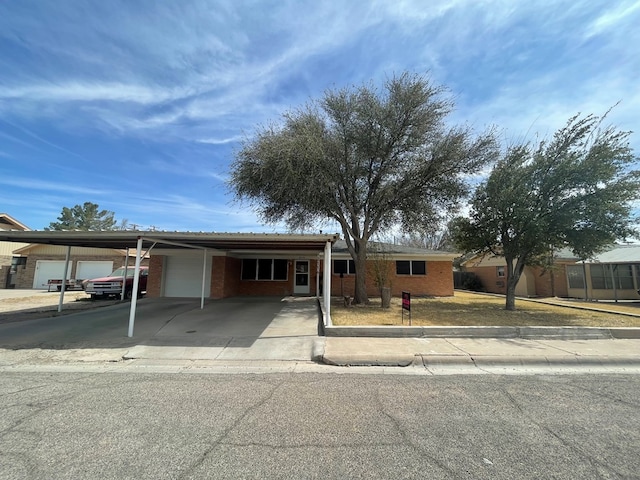 ranch-style home with an attached carport, brick siding, driveway, and an attached garage