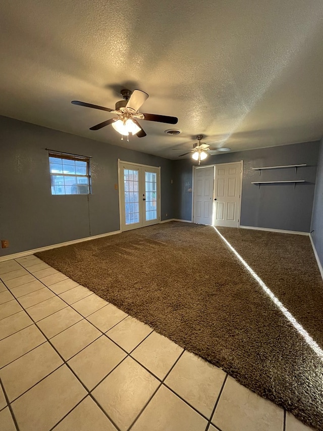 empty room with a textured ceiling, baseboards, visible vents, and light colored carpet