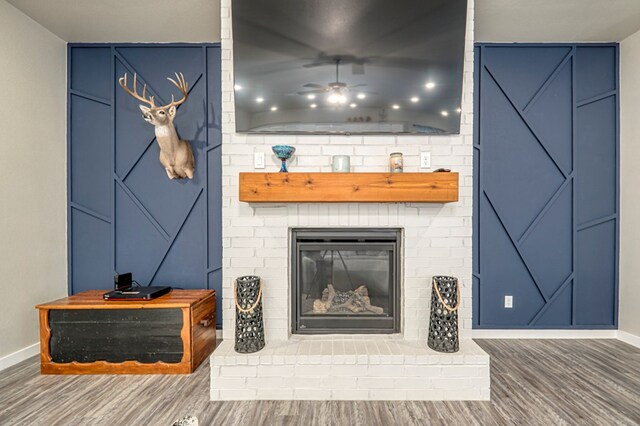 room details featuring ceiling fan, a fireplace, and wood-type flooring