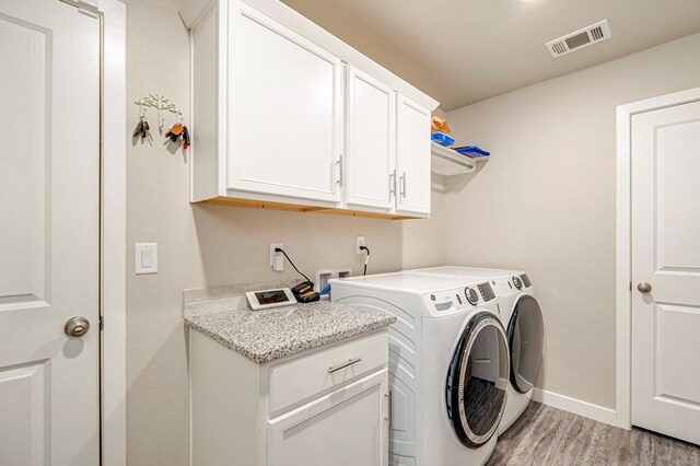 washroom featuring cabinets, separate washer and dryer, and light wood-type flooring