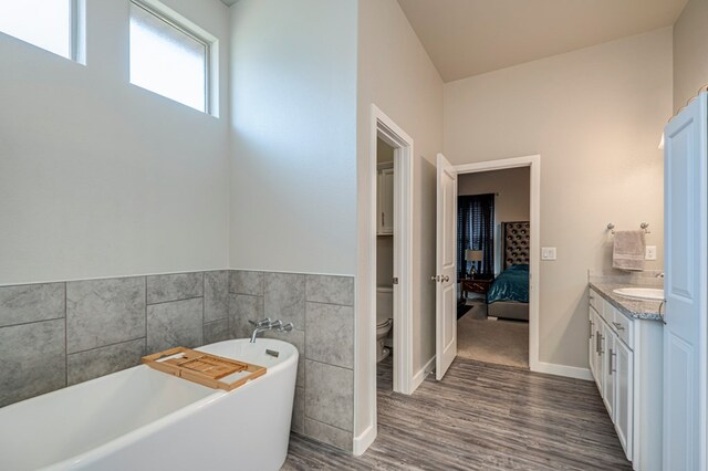 bathroom with vanity, hardwood / wood-style floors, a bathtub, and toilet