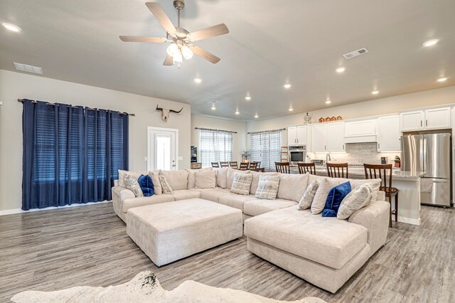 living room featuring light hardwood / wood-style flooring and ceiling fan