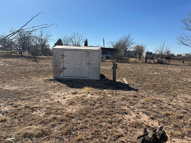 entry to storm shelter featuring an outbuilding, a rural view, fence, and a shed