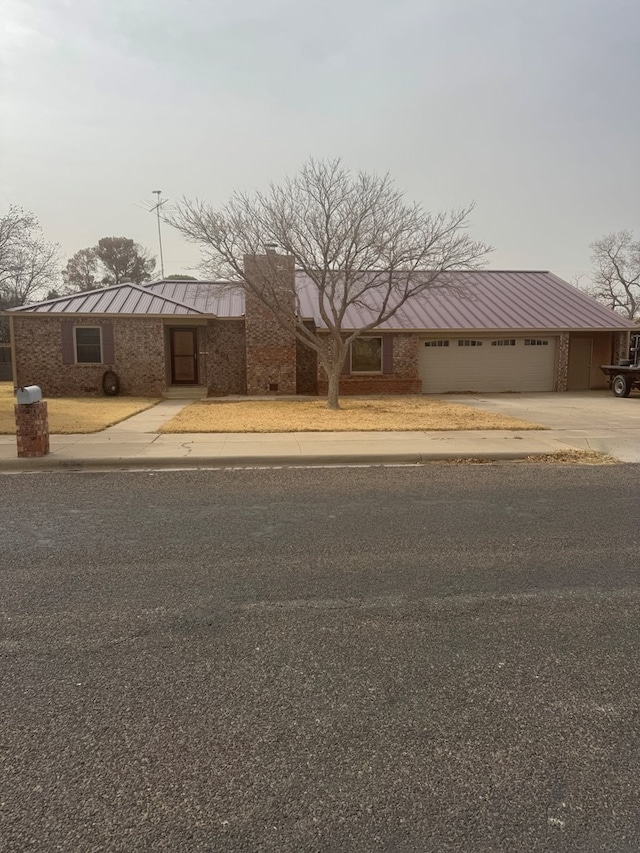 view of front of property featuring a garage, a standing seam roof, metal roof, and concrete driveway