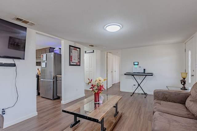 living room with a textured ceiling and light wood-type flooring