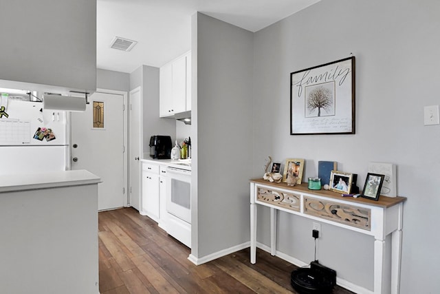 kitchen with dark hardwood / wood-style flooring, white cabinets, and white appliances