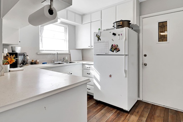 kitchen featuring dark wood-type flooring, sink, white cabinetry, white refrigerator, and kitchen peninsula