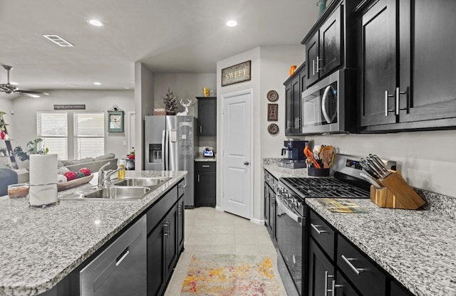 kitchen featuring light tile patterned flooring, appliances with stainless steel finishes, sink, ceiling fan, and a center island with sink