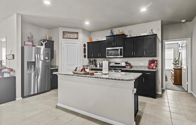 kitchen featuring light stone counters, appliances with stainless steel finishes, light tile patterned flooring, and a center island with sink