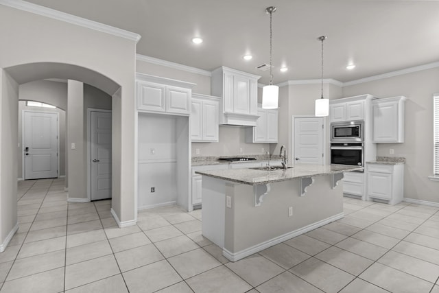 kitchen with light stone countertops, appliances with stainless steel finishes, sink, a center island with sink, and white cabinetry