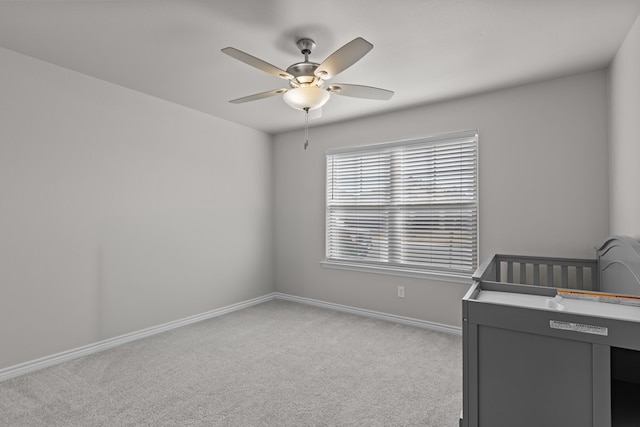 bedroom featuring ceiling fan, a nursery area, and light carpet