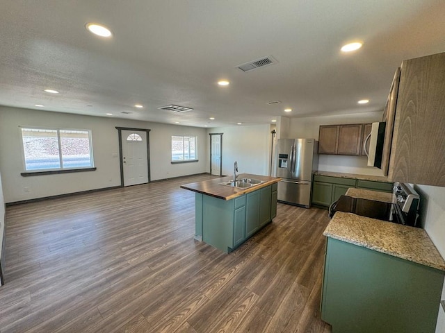 kitchen featuring a healthy amount of sunlight, dark wood-type flooring, stainless steel appliances, and an island with sink