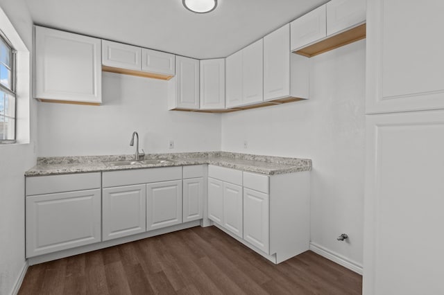 kitchen with white cabinetry, dark wood-type flooring, sink, and light stone counters