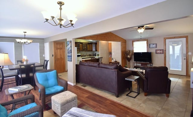 living room featuring vaulted ceiling, ceiling fan with notable chandelier, and light wood-type flooring