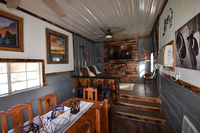 dining space with ceiling fan, wood walls, dark wood-type flooring, and a wall unit AC