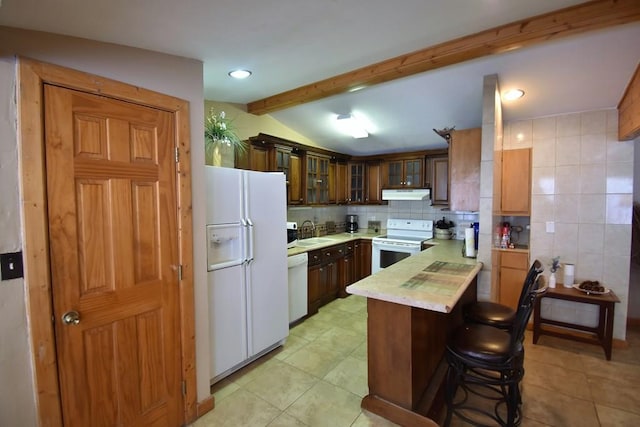 kitchen with kitchen peninsula, a kitchen bar, white appliances, sink, and vaulted ceiling with beams