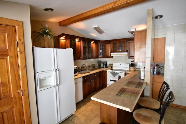 kitchen featuring lofted ceiling with beams, a kitchen breakfast bar, white appliances, and kitchen peninsula