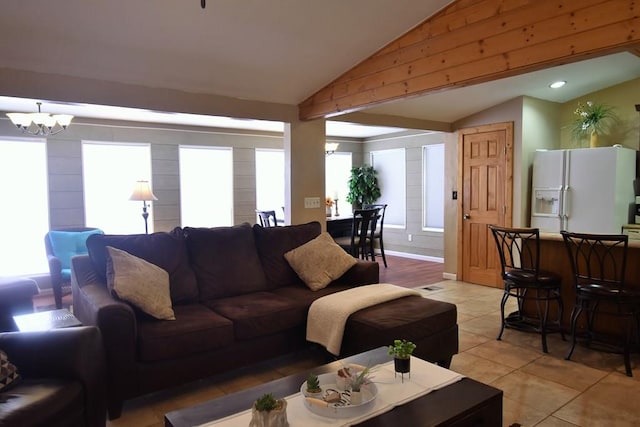 tiled living room featuring plenty of natural light, vaulted ceiling, and a notable chandelier