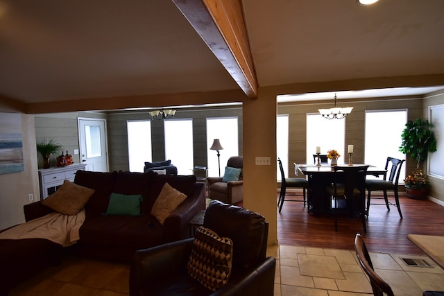 living room with beam ceiling, a healthy amount of sunlight, wood-type flooring, and an inviting chandelier