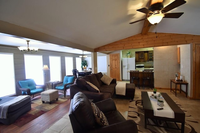 living room with ceiling fan with notable chandelier, lofted ceiling with beams, light hardwood / wood-style flooring, and wood walls