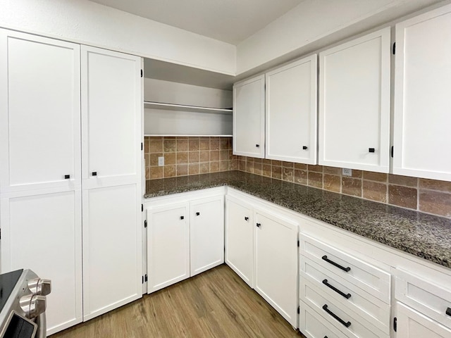 kitchen with backsplash, light wood-style flooring, dark stone countertops, and open shelves