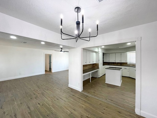 kitchen with dark countertops, backsplash, open floor plan, and dark wood-style flooring