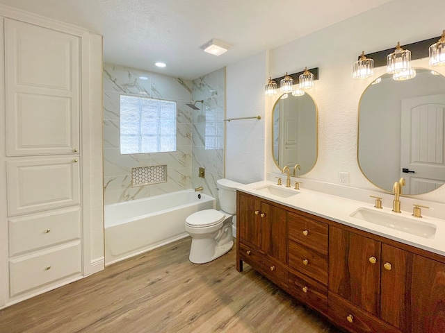 bathroom with toilet, double vanity, a sink, and wood finished floors