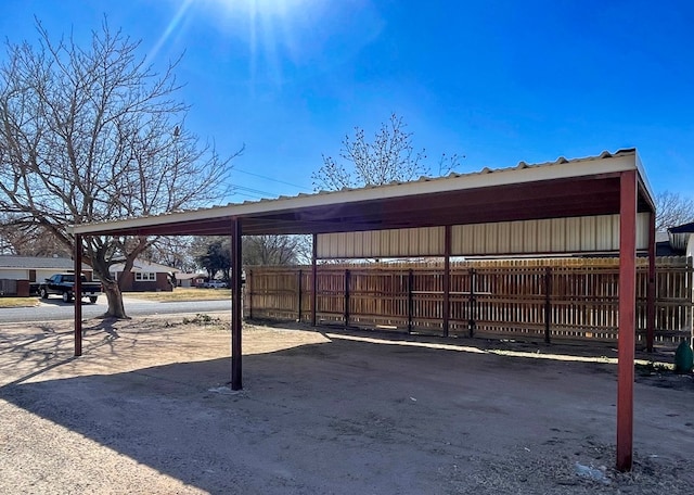 view of parking / parking lot with fence and a detached carport