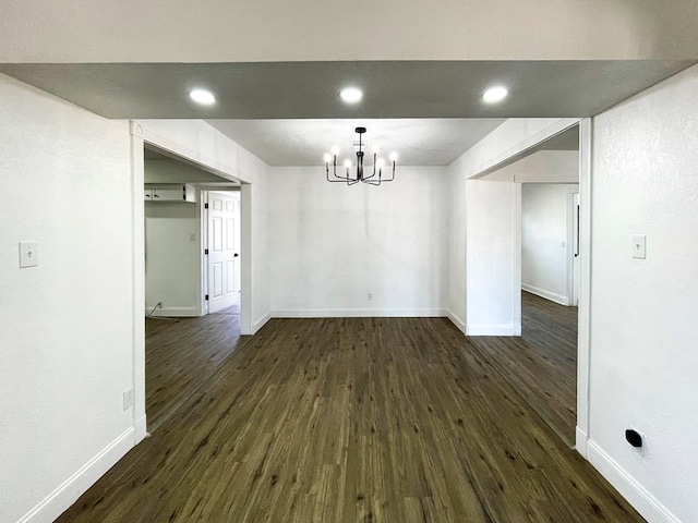 unfurnished dining area featuring recessed lighting, dark wood-style flooring, an inviting chandelier, and baseboards