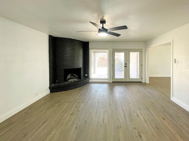 unfurnished living room featuring a textured ceiling, french doors, a fireplace, and wood finished floors