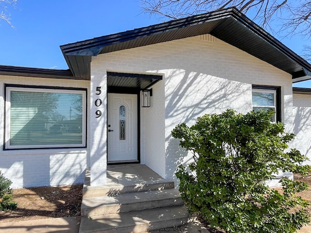 doorway to property featuring brick siding