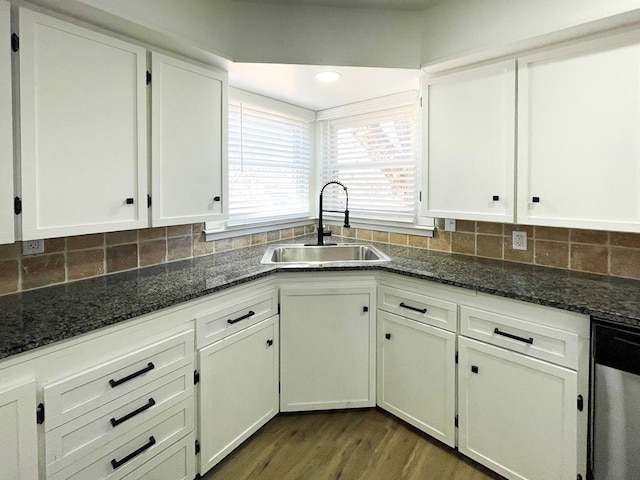 kitchen with tasteful backsplash, white cabinetry, a sink, dark stone counters, and dishwasher