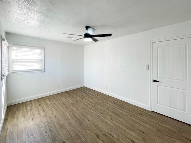 unfurnished room featuring visible vents, baseboards, a ceiling fan, wood finished floors, and a textured ceiling